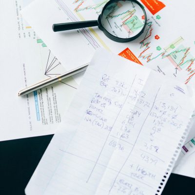 Financial documents and charts with a magnifying glass, symbolizing analysis and data review.
